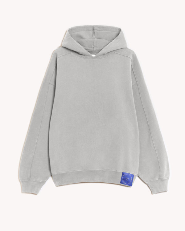Imagen de la parte delantera de la hoodie modelo Cistierna con capucha en color gris claro. En la parte izquierda del elástico inferior de la sudadera lleva cosido en tela el logo de hoodies with heart. Modelo unisex de corte holgado y hombro caído.