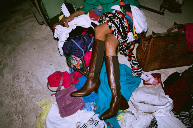 Persona rodeada de ropa como símbolo del consumo excesivo y la moda ultrarrápida en Europa
